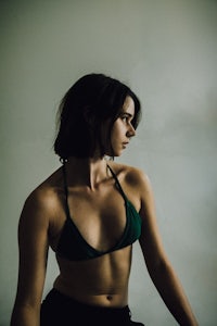 a woman in a green bikini posing in front of a wall