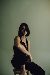 a woman sitting on a stool in front of a wall