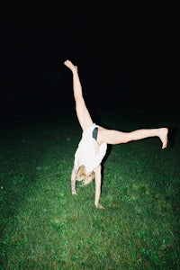 a woman doing a handstand in the grass