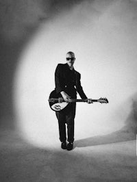a black and white photo of a man holding a guitar
