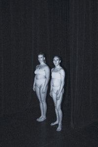 two naked women standing in a dark room