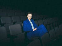 a man in a blue suit sitting in an empty theater