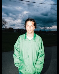 a man in a green jacket standing on a street