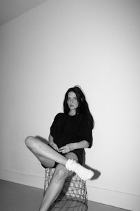 a woman sitting on a chair in a white room