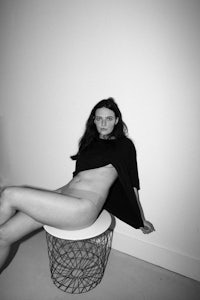 a woman sitting on a stool in a room