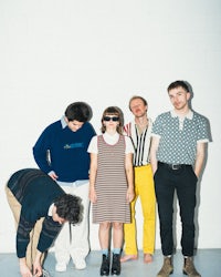 a group of people standing in front of a white wall
